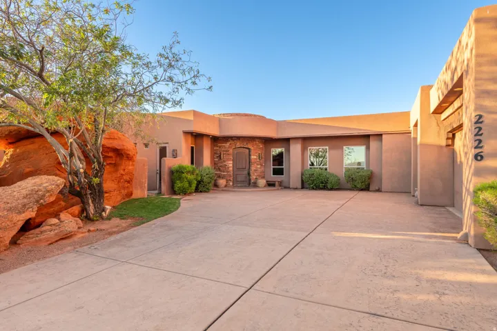 Southwest-style home featuring stucco siding, stone siding, and driveway