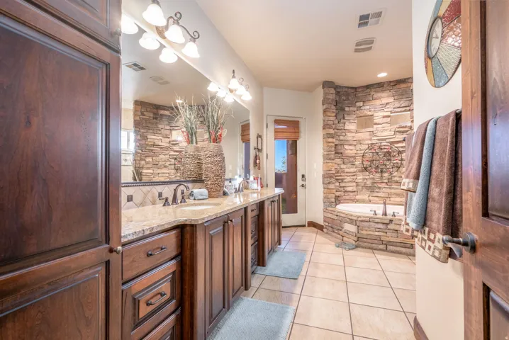 Bathroom featuring double vanity, a bath, light tile patterned flooring, and a chandelier
