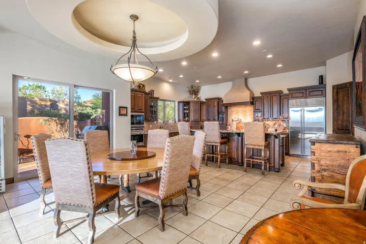 Dining area with a tray ceiling, recessed lighting, and light tile patterned floors