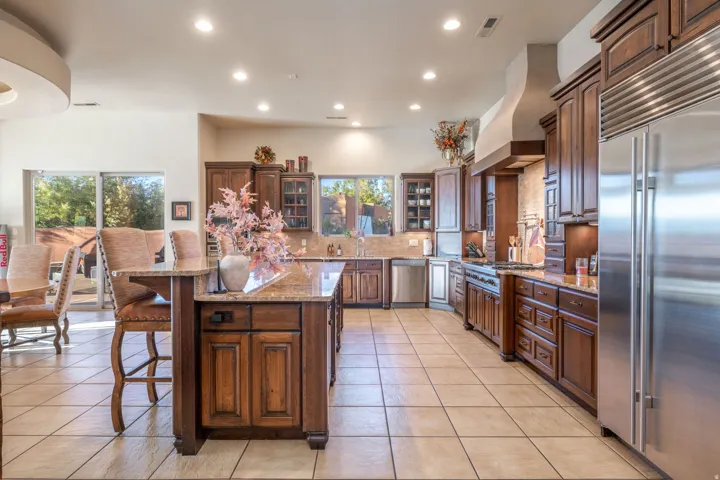 Kitchen featuring glass insert cabinets, appliances with stainless steel finishes, light stone counters, a breakfast bar area, and recessed lighting