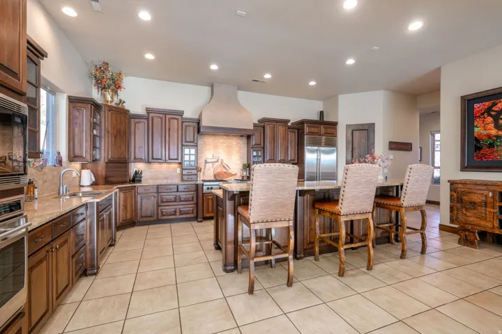 Kitchen with tasteful backsplash, light tile patterned floors, light stone counters, recessed lighting, and built in appliances