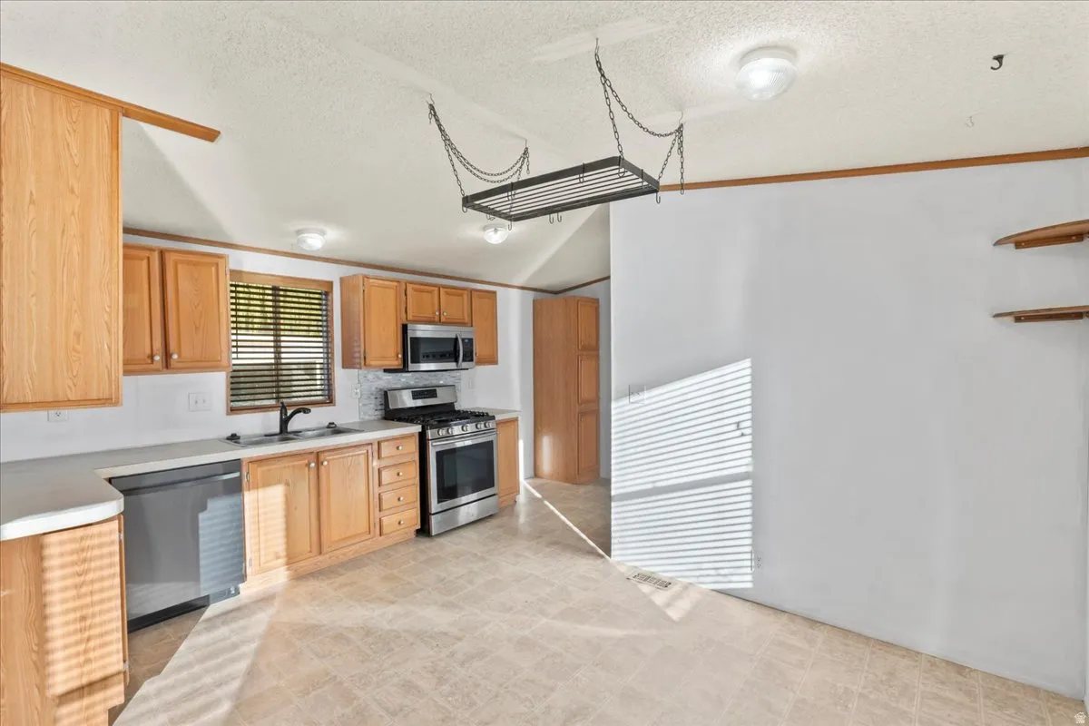 Kitchen with appliances with stainless steel finishes, light countertops, a textured ceiling, and backsplash