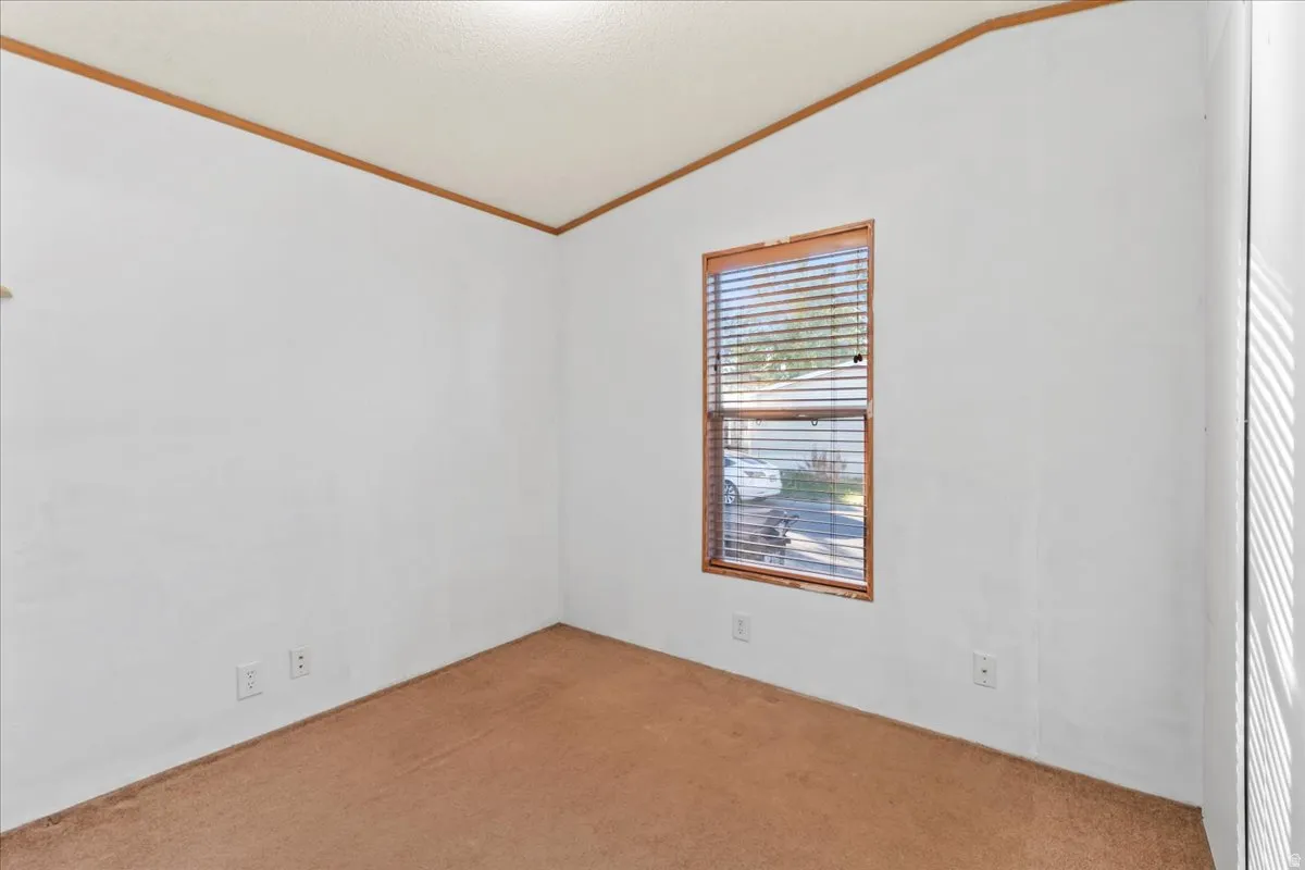Carpeted spare room with vaulted ceiling and ornamental molding