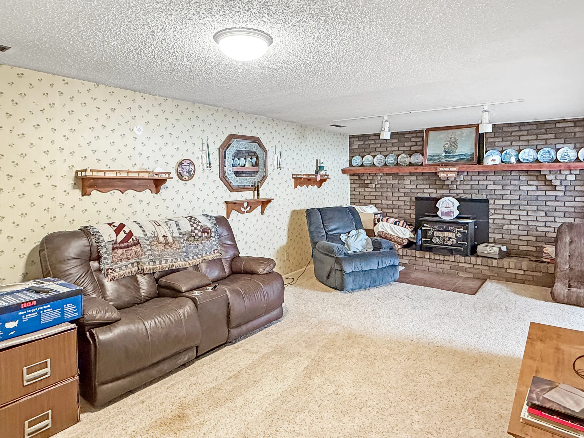 Carpeted living area featuring a textured ceiling, a wood stove, and track lighting