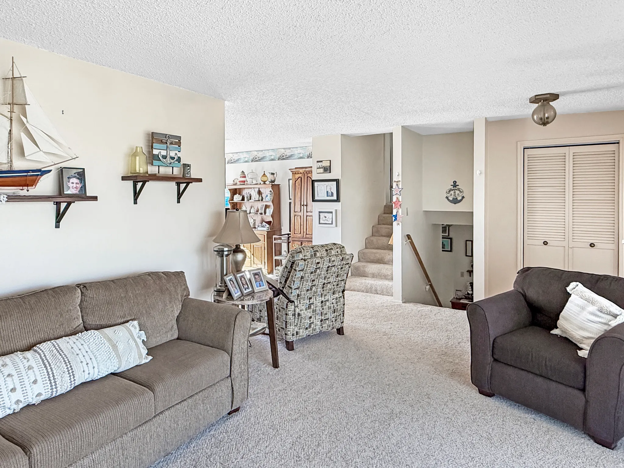 Living room featuring carpet floors, stairway, and a textured ceiling
