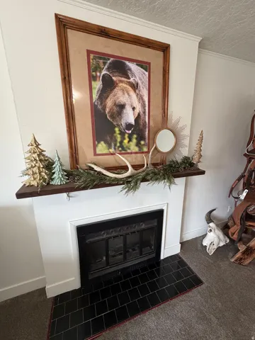 Detailed view of a tiled fireplace, ornamental molding, newly carpeted floors.