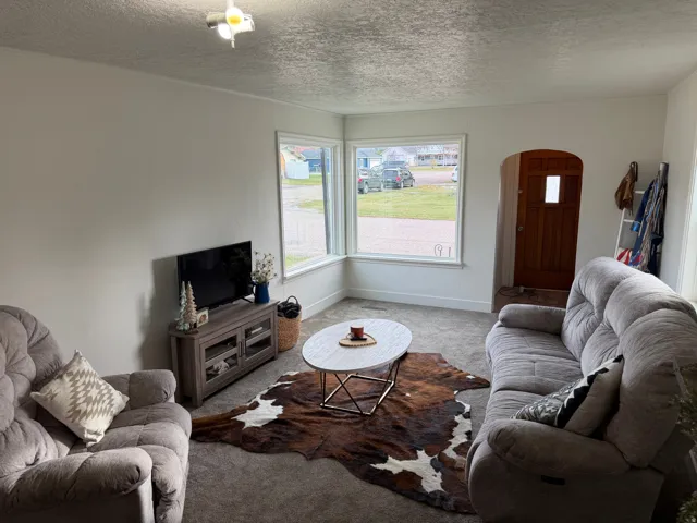 Carpeted living room featuring arched walkways and large picture windows.