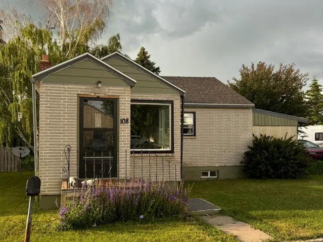 View of front of home with a front lawn, brick siding, a chimney, and roof with shingles