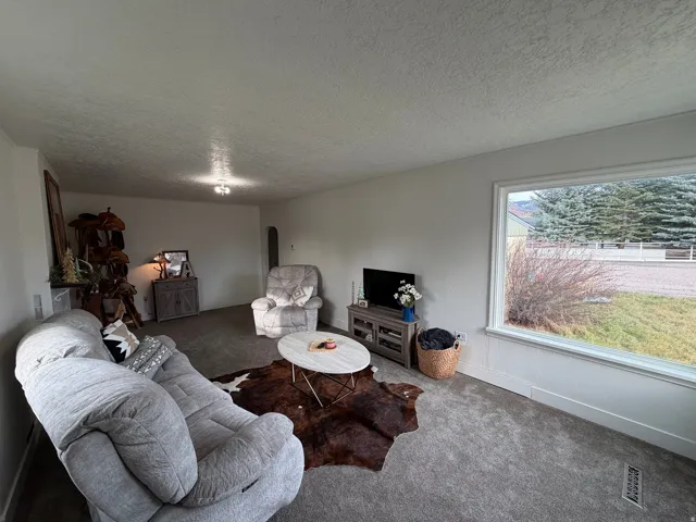 Carpeted living room with arched walkways and large picture windows.