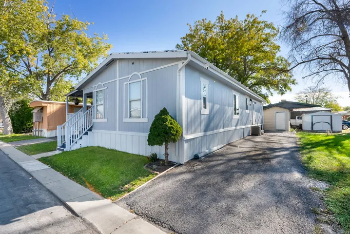 View of side of home with a lawn, a storage unit, and driveway