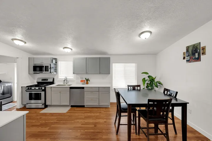 Kitchen with gray cabinetry, appliances with stainless steel finishes, light countertops, light wood finished floors, and healthy amount of natural light