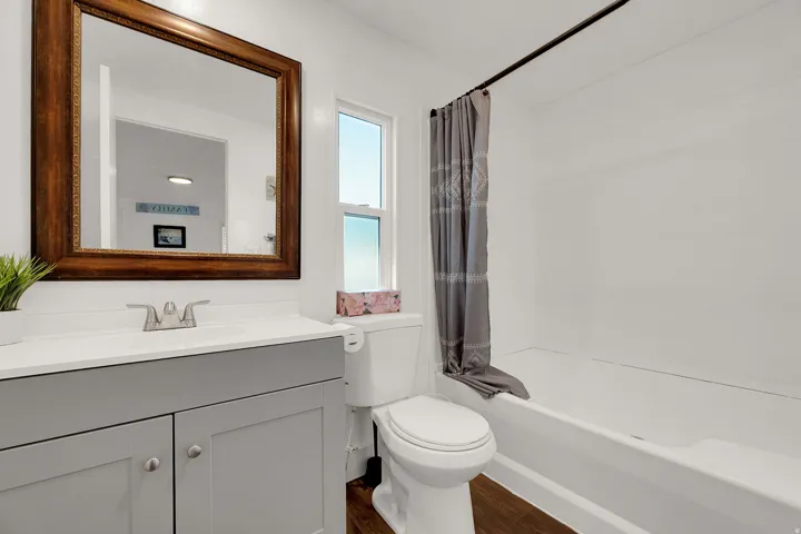 Bathroom with shower / tub combo with curtain, dark wood-style flooring, and vanity