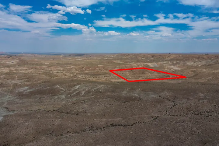 Expansive undeveloped land featuring a rugged, arid terrain with distant hills