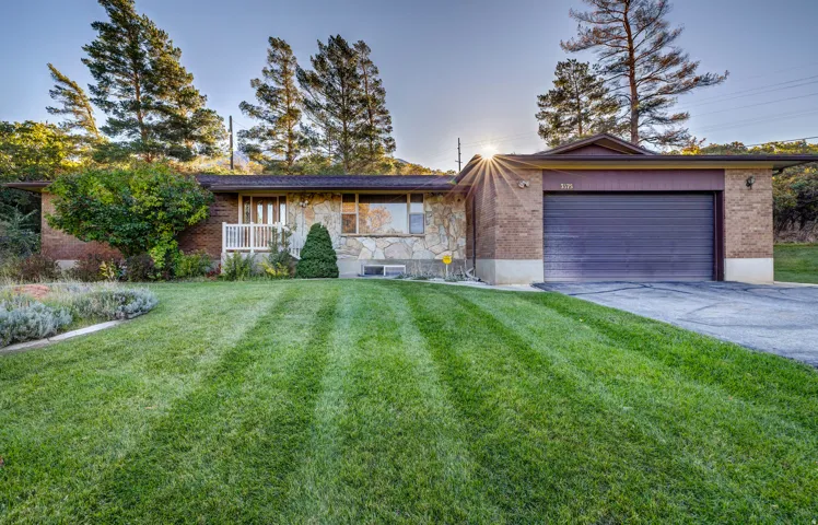 Single story home featuring a front lawn, driveway, brick siding, and an attached garage