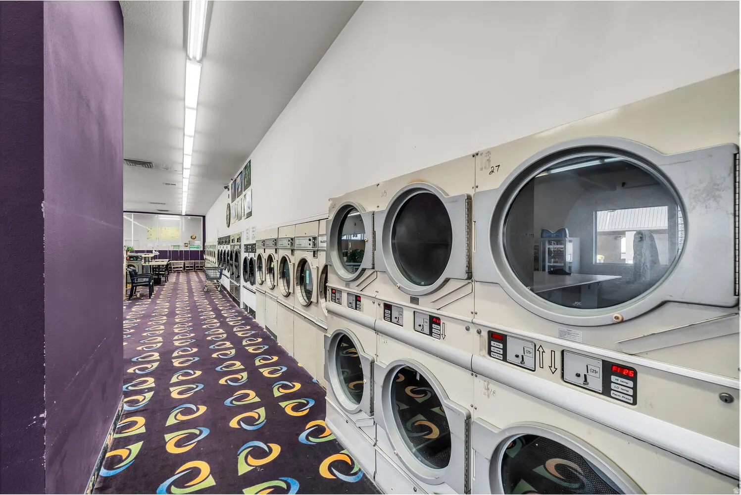 Shared laundry room with stacked washing machine and dryer and separate washer and dryer