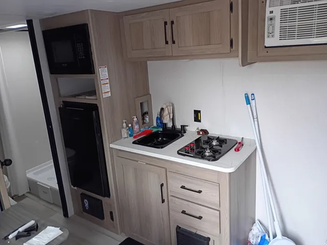 Kitchen featuring light countertops, black microwave, light brown cabinets, and gas stovetop
