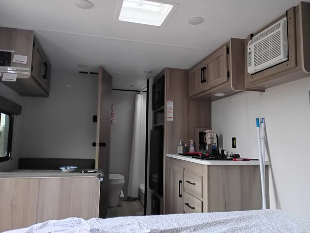 Kitchen with light countertops, a wall mounted AC, light brown cabinetry, and wood finished floors
