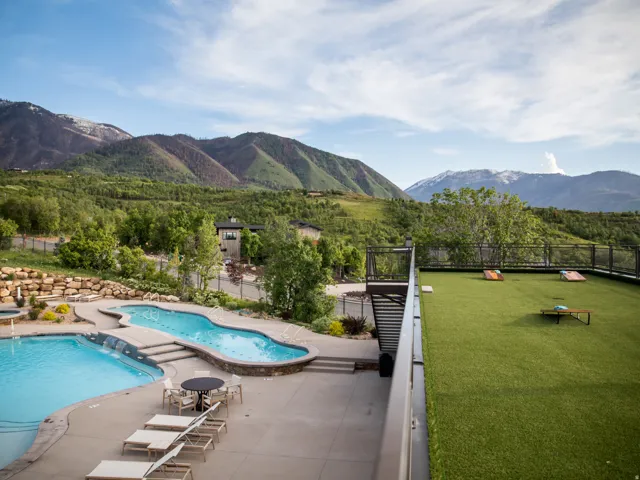 Community pool with a mountain view, a patio area, and a view of trees