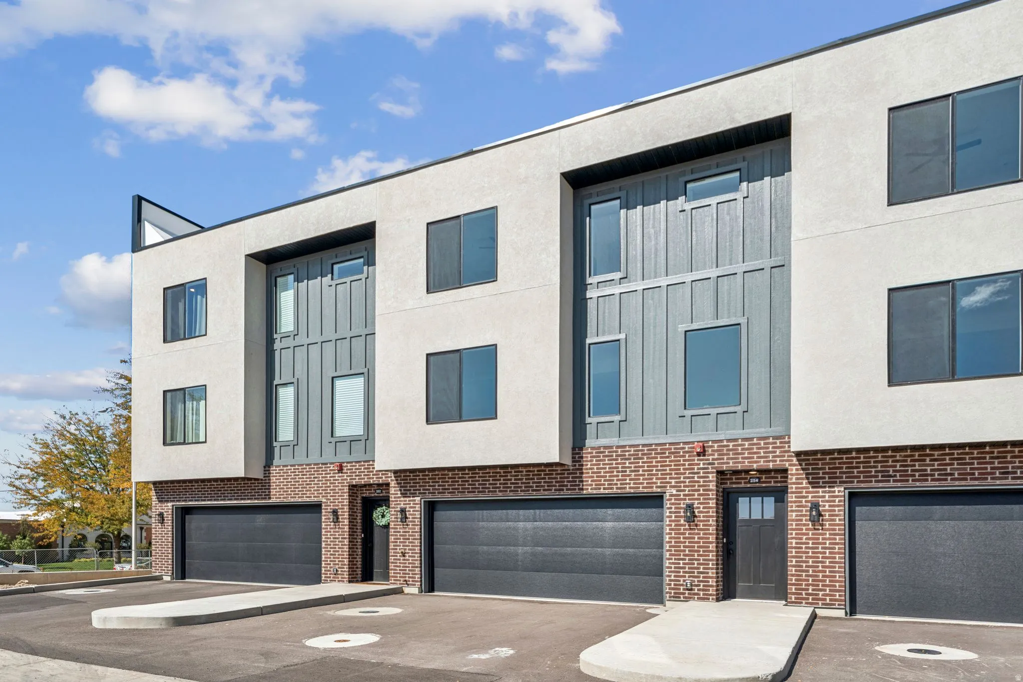 Contemporary home featuring board and batten siding, brick siding, an attached garage, and driveway