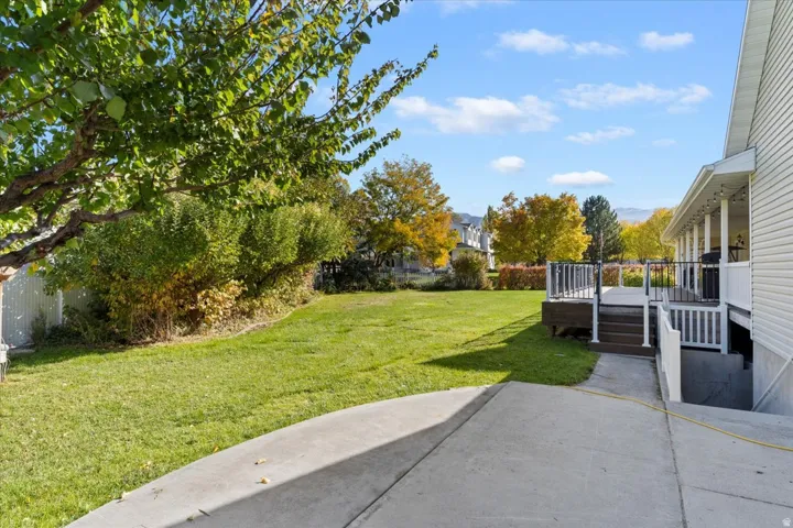 View of green lawn featuring a patio and a deck
