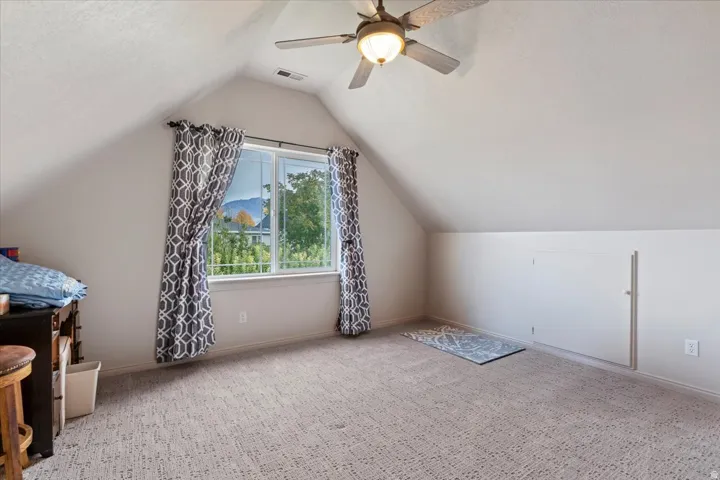 Bonus room with vaulted ceiling, carpet flooring, ceiling fan, and a textured ceiling
