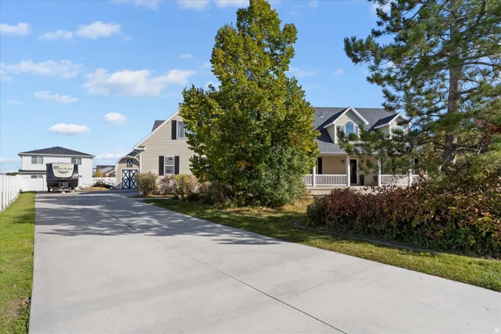 View of property hidden behind natural elements featuring driveway and a front yard