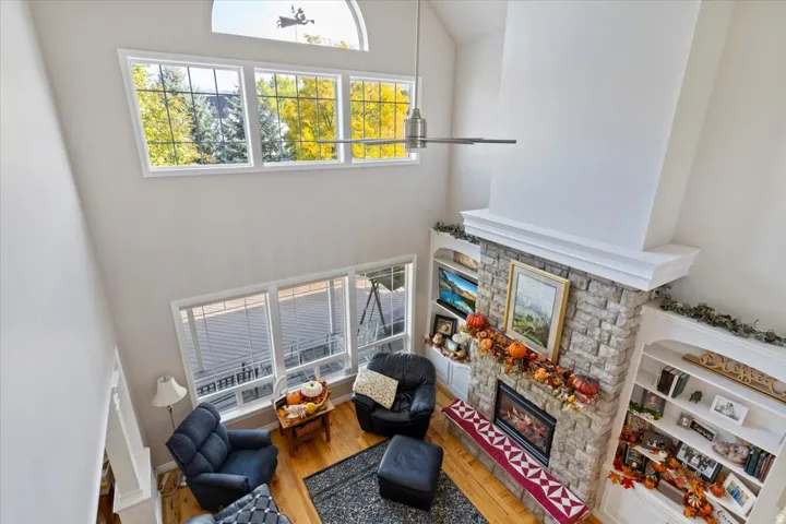 Living area featuring high vaulted ceiling, wood finished floors, a fireplace, and plenty of natural light