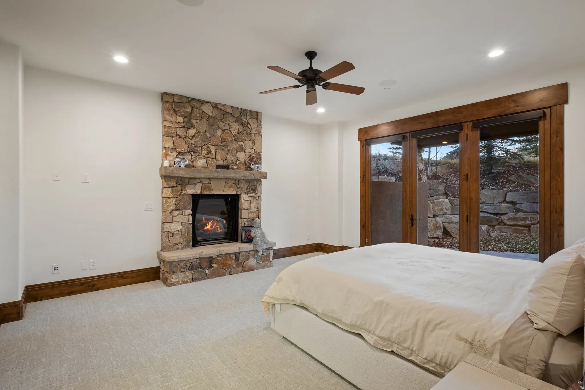 Bedroom with access to exterior, carpet, a fireplace, and a ceiling fan