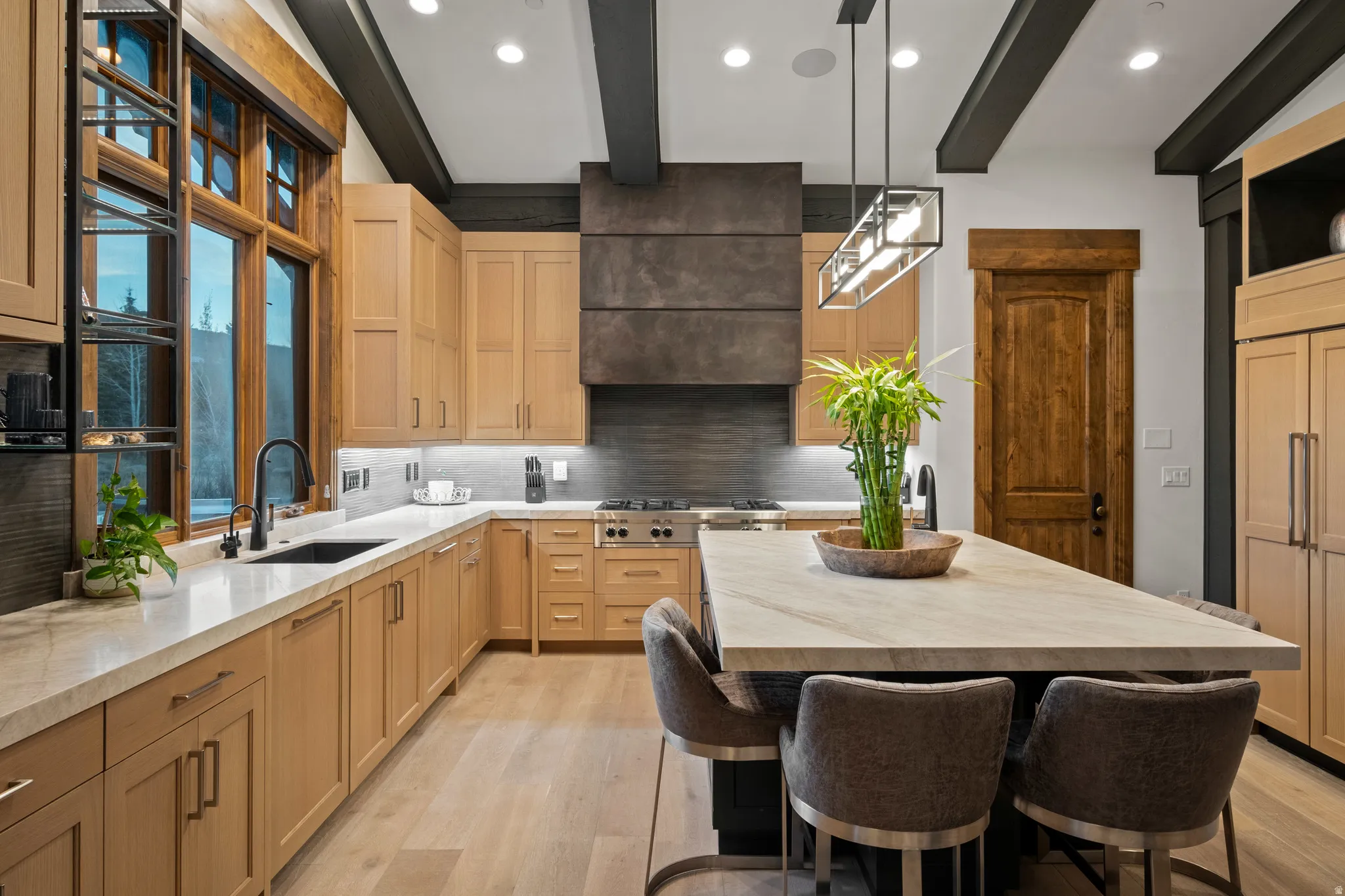 Kitchen featuring a kitchen bar, a center island, light wood finish cabinetry, decorative light fixtures, and beam ceiling