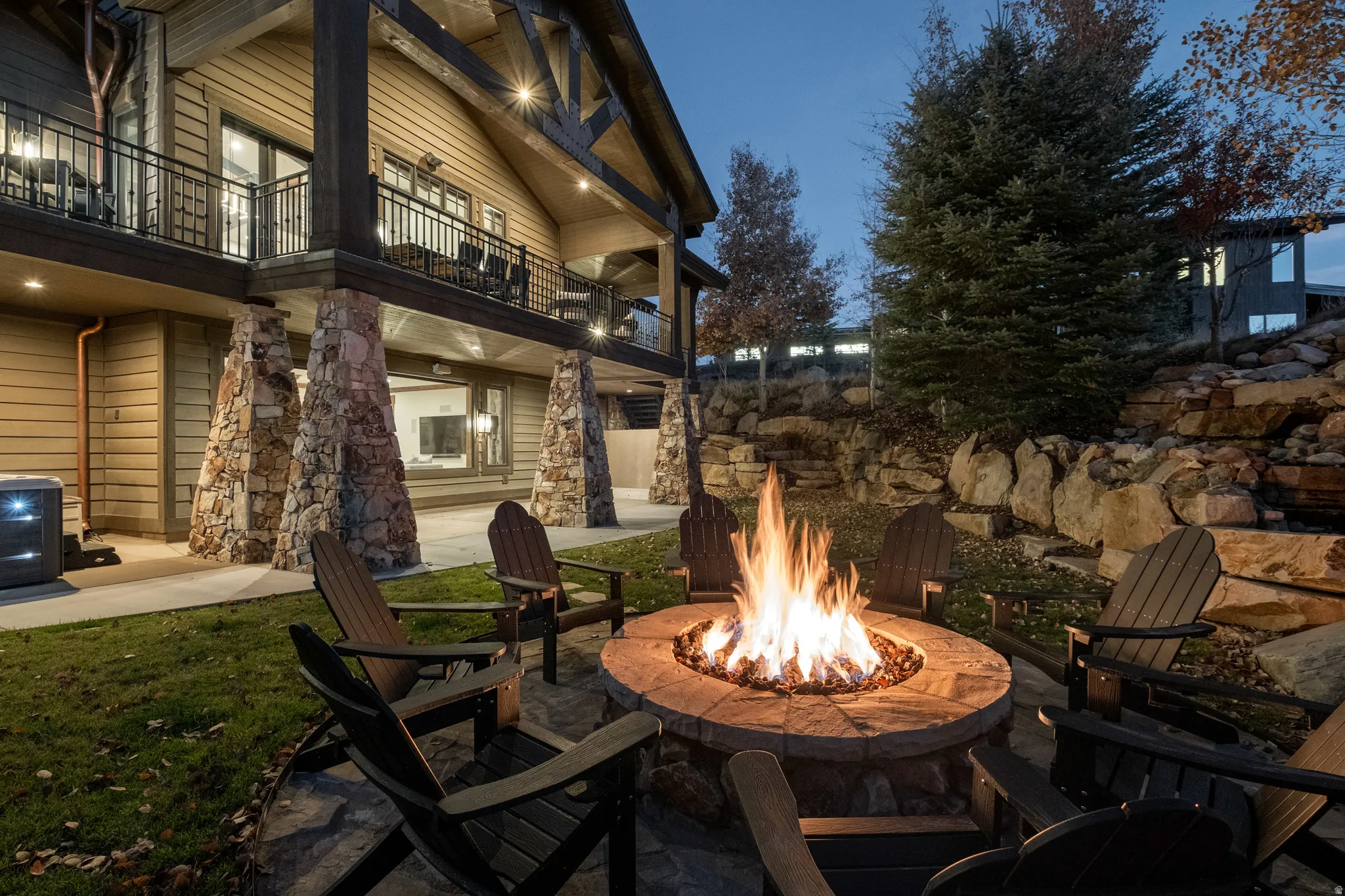 Patio at night featuring a balcony, a patio, and a fire pit
