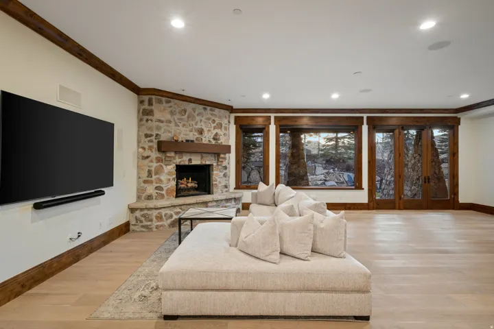 Living area with light wood-style floors, crown molding, a stone fireplace, and recessed lighting