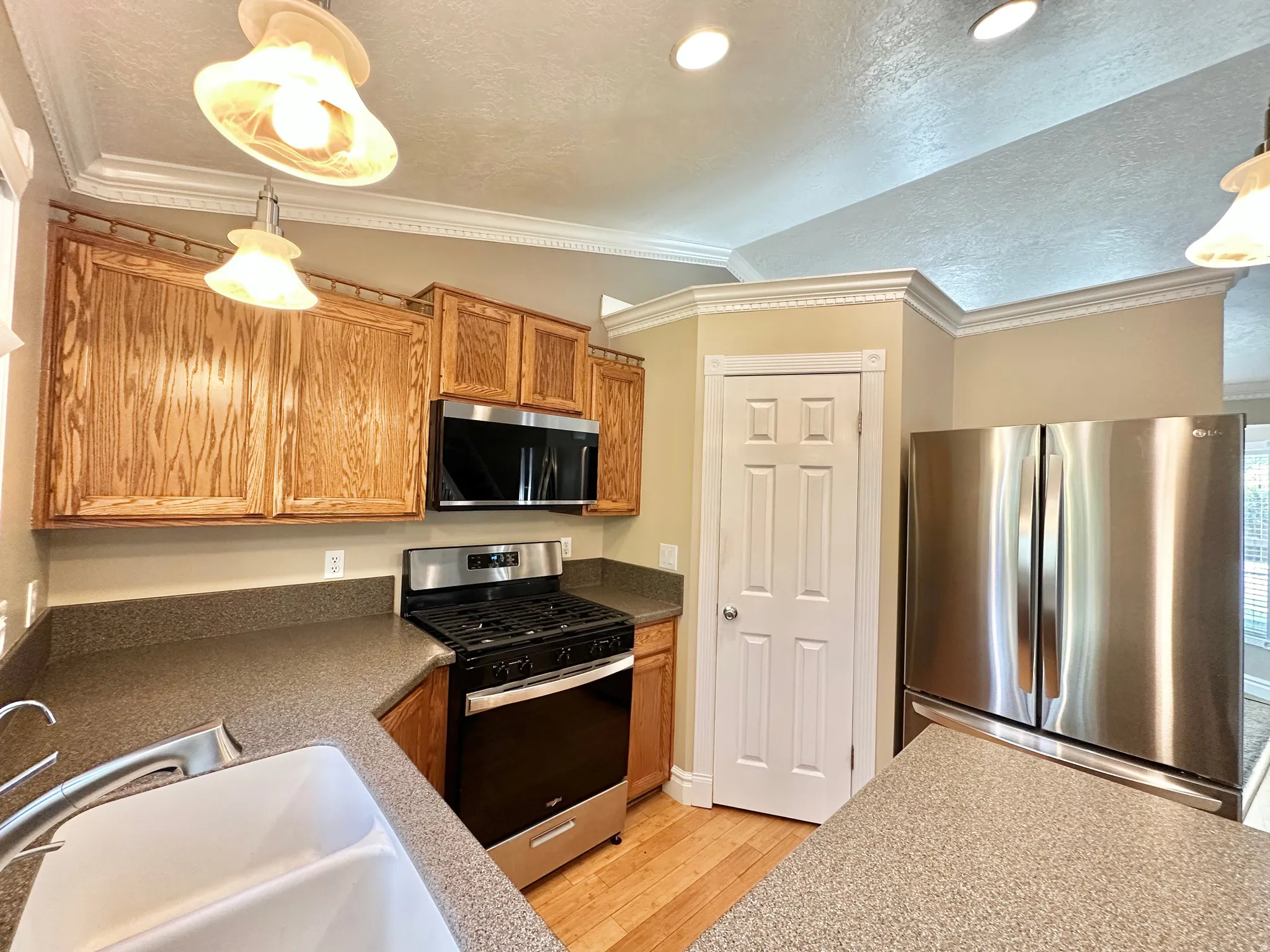 Kitchen featuring ornamental lighting, single surface Corian counters, new appliances, and pantry