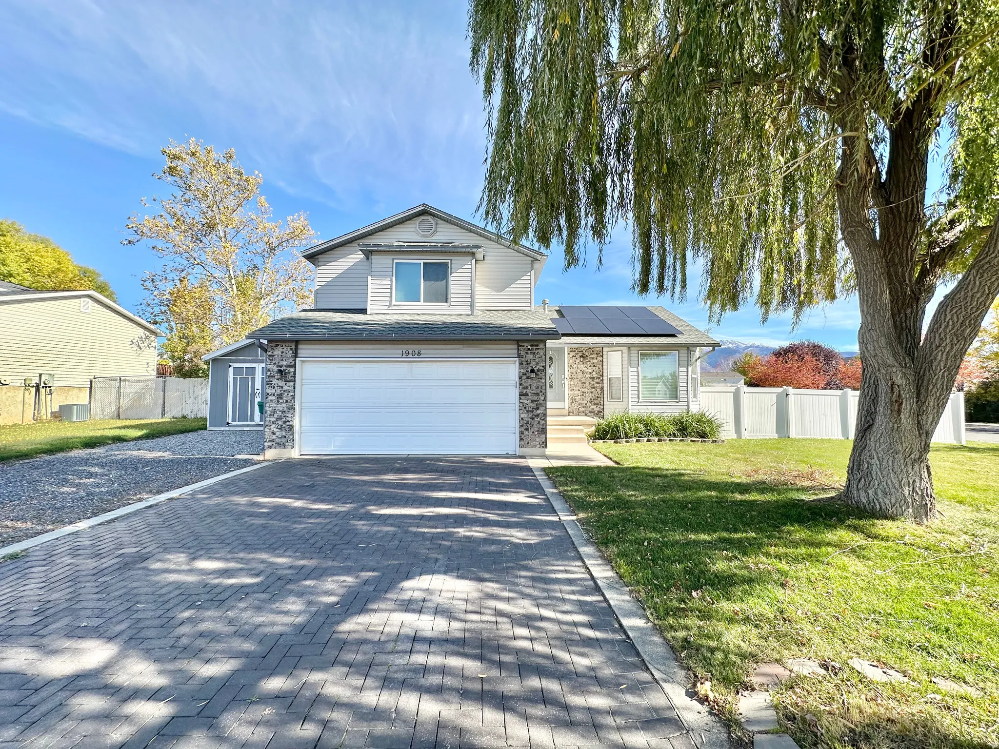 Traditional home featuring roof mounted solar panels, decorative driveway, and an attached garage