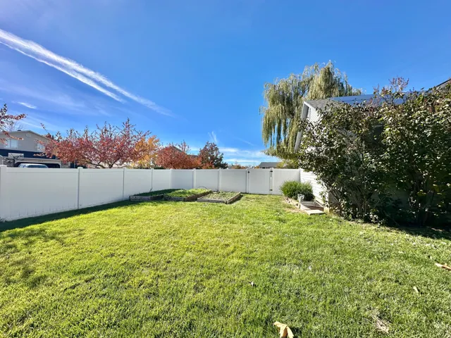 Fenced backyard with GATE near garden boxes.