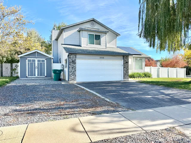Traditional-style house featuring roof mounted solar panels, driveway, a garage.