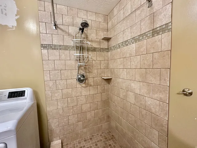 Bathroom featuring washer / clothes dryer and a tile shower
