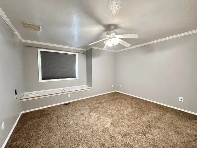 Primary bedroom with ceiling fan, blackout shades and storage under window seat