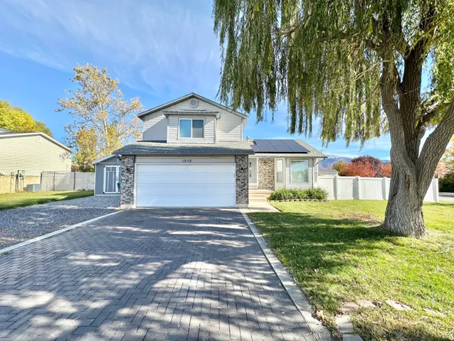 Traditional home featuring roof mounted solar panels, decorative driveway, and an attached garage