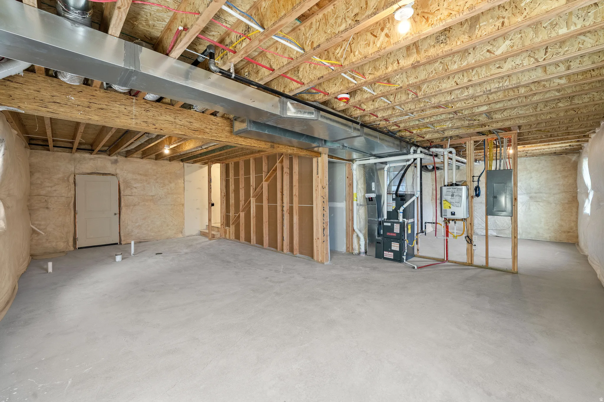 Unfinished basement with water heater, electric panel, and heating unit