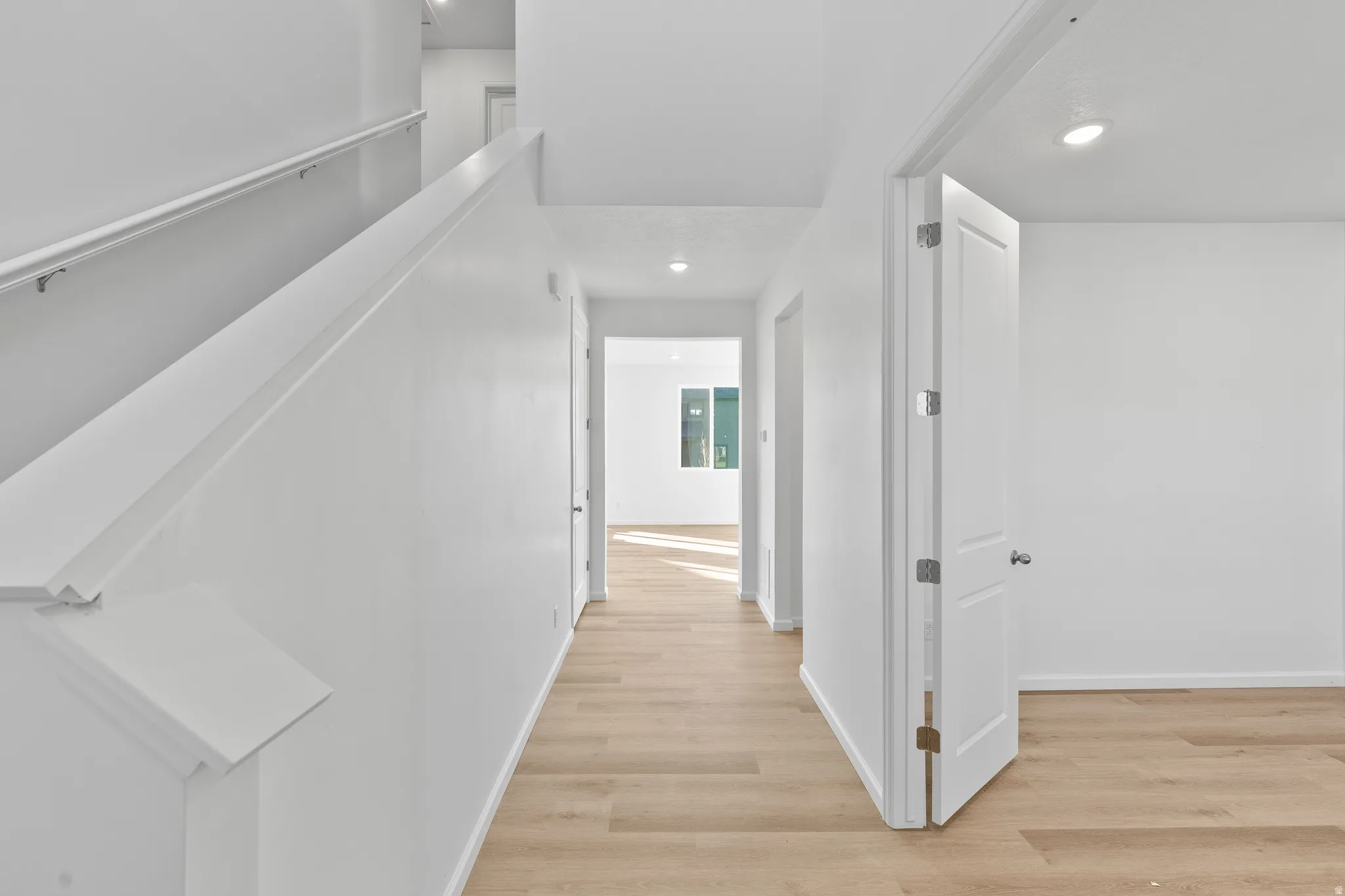 Corridor with light wood-style flooring and recessed lighting