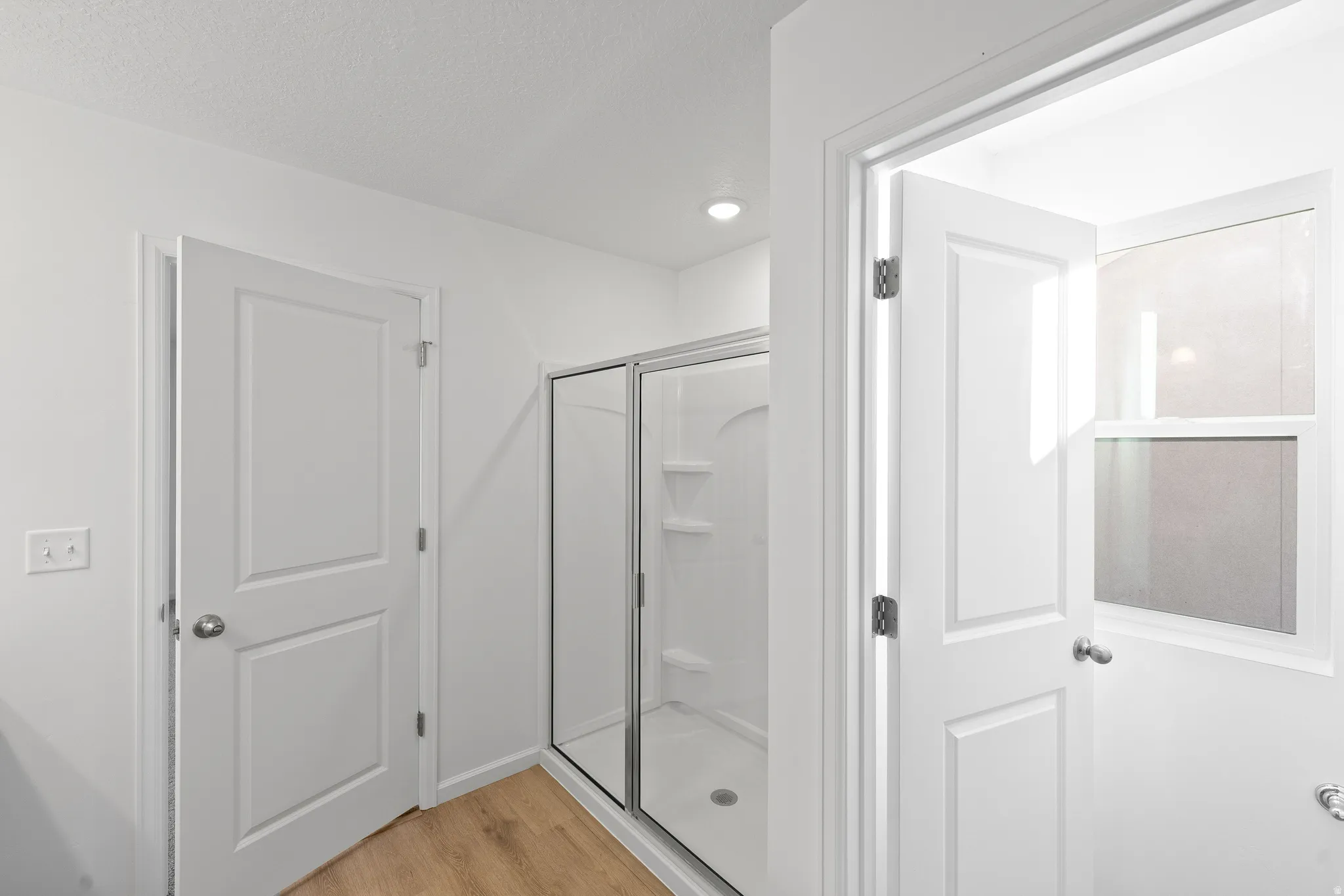 Bathroom featuring light wood-type flooring, a stall shower, and recessed lighting