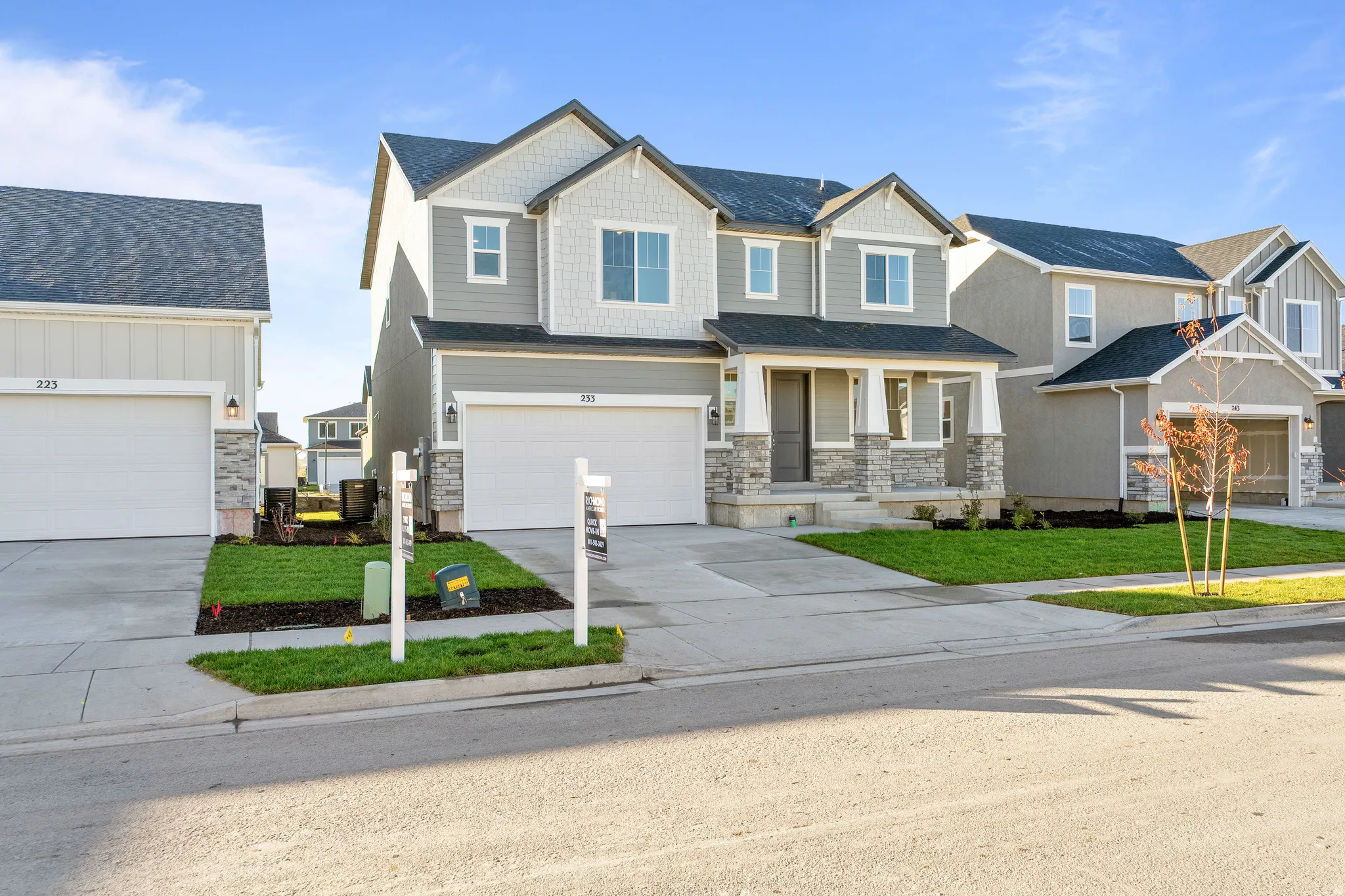 Craftsman-style house with covered porch, concrete driveway, stone siding, a residential view, and a front lawn