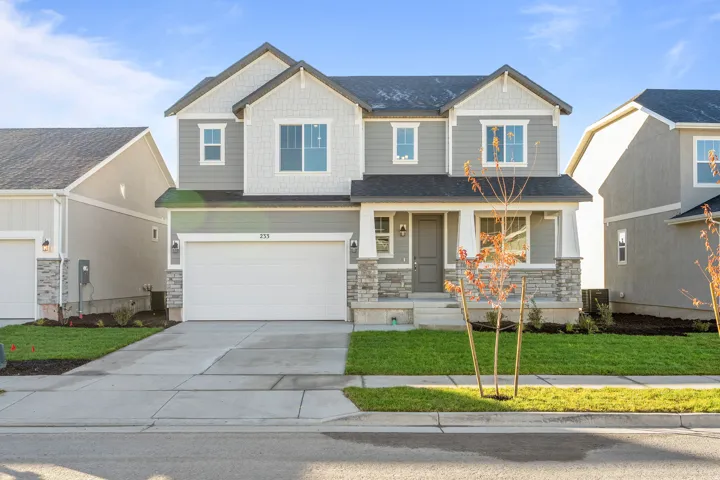 Craftsman inspired home featuring a porch, stone siding, driveway, a front lawn, and a garage