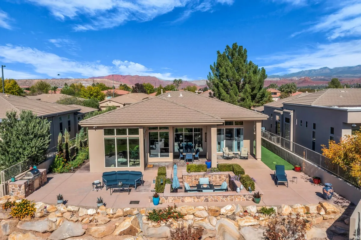 Rear view of house with exterior kitchen, a patio area, a mountain view, and an outdoor living space with a fire pit