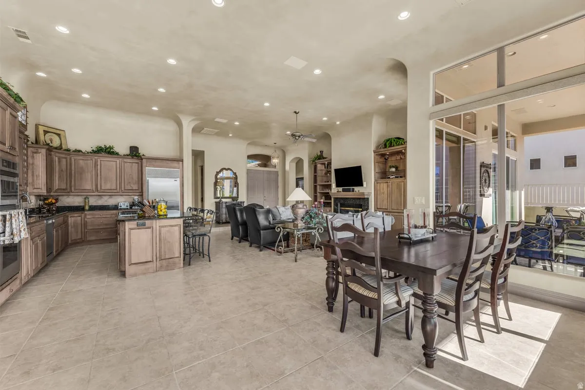 Dining area with recessed lighting, ceiling fan, arched walkways, light tile patterned floors, and a fireplace