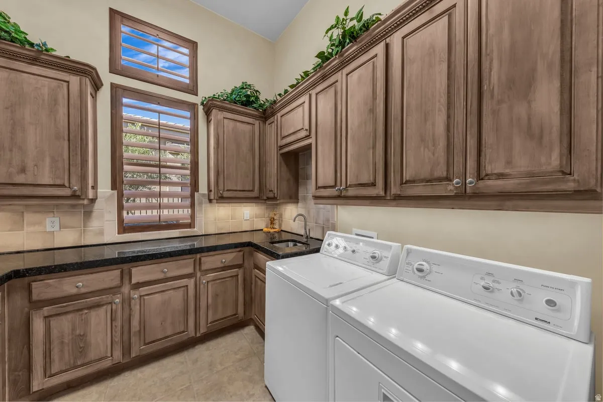 Laundry area with separate washer and dryer, cabinet space, and light tile patterned floors