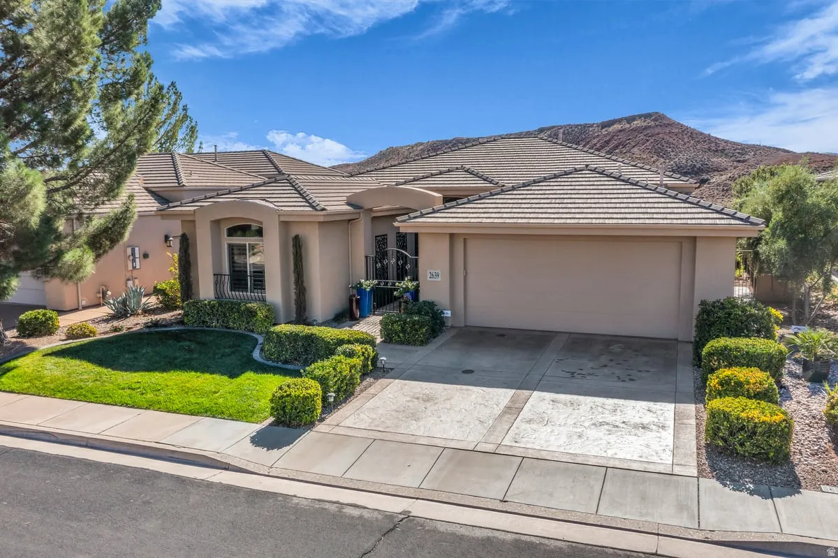 View of front facade with driveway, a front lawn, stucco siding, and an attached garage