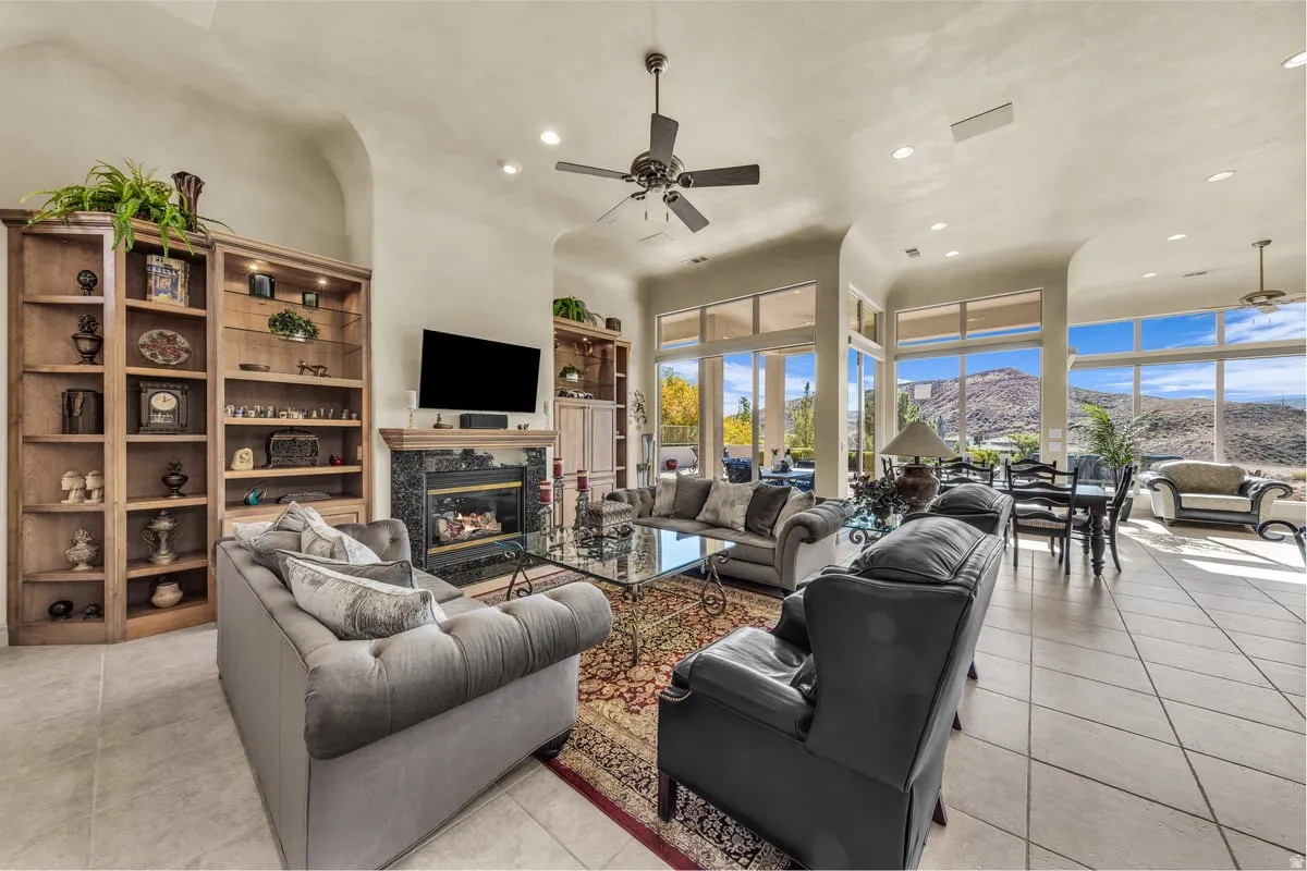 Living room featuring a ceiling fan, recessed lighting, light tile patterned flooring, and a fireplace