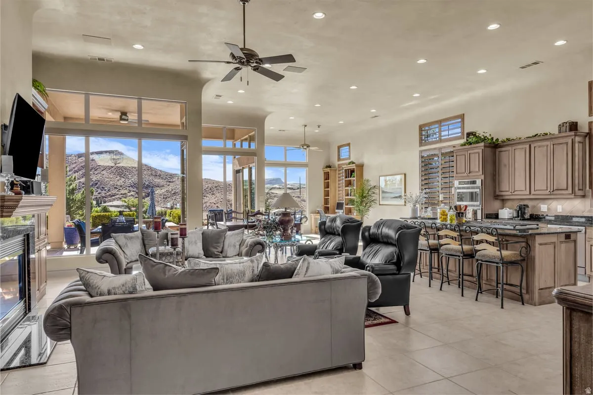 Living room featuring a mountain view, recessed lighting, a premium fireplace, ceiling fan, and a high ceiling
