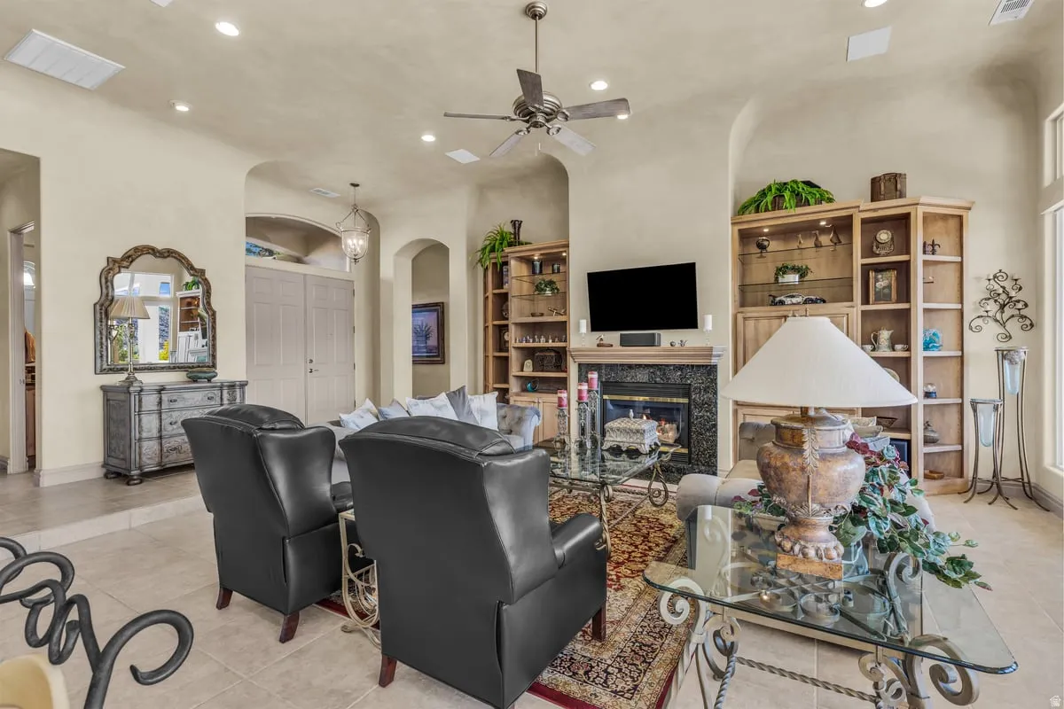 Living room featuring recessed lighting, light tile patterned floors, ceiling fan, a fireplace, and arched walkways